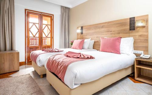 a bedroom with two beds with pink and white pillows at Hotel Oudaya & Spa in Marrakech