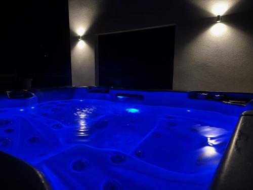 - un bain à remous bleu dans une chambre sombre éclairée dans l'établissement La Vallée des Biches G1, à Saint-Martin-Boulogne