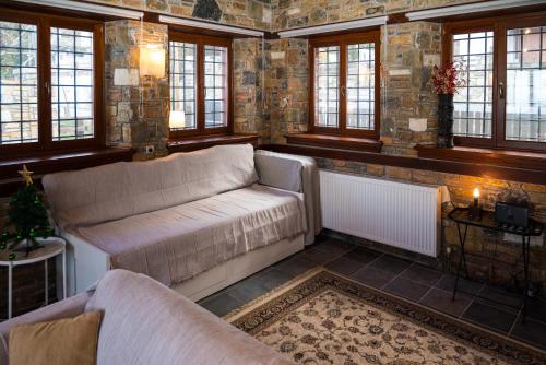 a living room with two couches and windows at Venieri's Stone Villa in Tsagarada