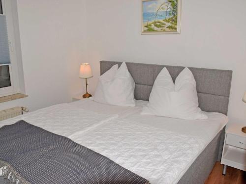 a bed with white pillows on it in a room at Ferienwohnung Gartenblick in Altefähr