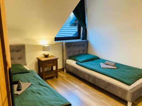 a small room with two beds and a window at Modryna - Modrzewiowy Dom in Cisna