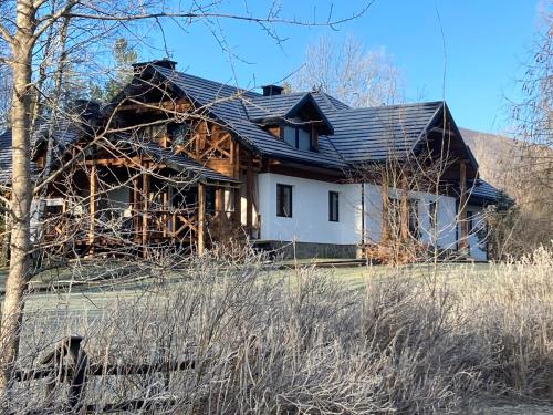 a log home with a black roof at Modryna - Modrzewiowy Dom in Cisna