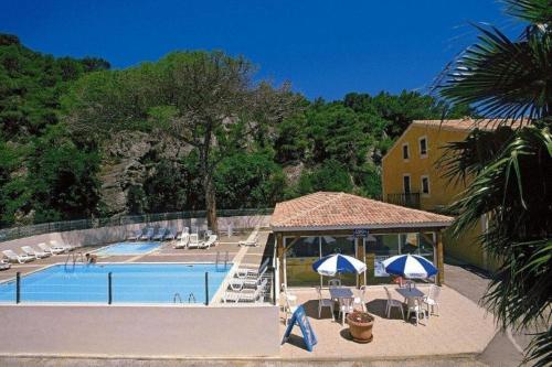 une piscine avec des chaises et des parasols et un bâtiment dans l'établissement NP045-018 Appartement 2 pièces, Narbonne Plage, à Narbonne-Plage