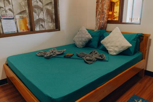 a bed with green sheets and pillows on it at Nay Carmen Pension House Port Barton in Itaytay