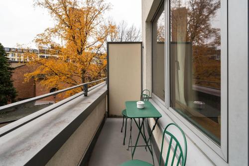 a green table and chairs on a balcony with a window at Numa Berlin Potsdamer Platz in Berlin