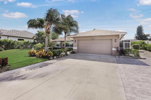 a house with a garage and a palm tree at Quiet inland home with pool, two queen beds and grill in Marco Island