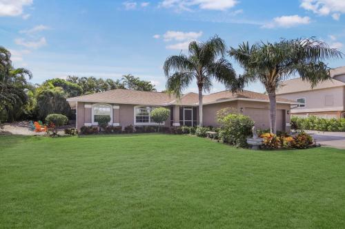 a house with palm trees in a yard at Quiet inland home with pool, two queen beds and grill in Marco Island