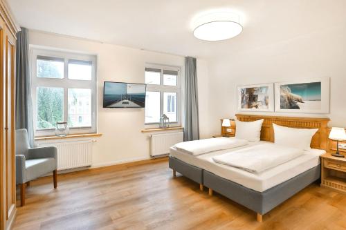 a bedroom with a bed and a chair and windows at Apartments an Sankt Marien in Stralsund
