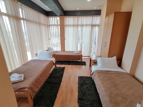 two beds in a room with large windows at Hotel Talija in Svilajnac