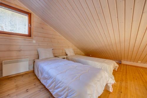 two beds in a room with wooden walls and a window at Holiday Apartments Kruunurinne 1 & 2 in Himos
