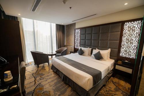 a hotel room with a large bed and a chair at Aster Hotel in Jeddah