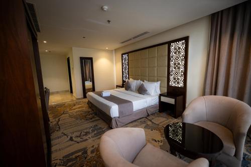 a hotel room with a bed and two chairs at Aster Hotel in Jeddah