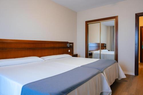 a bedroom with a large bed and a mirror at Port Europa in Calpe