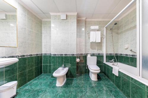 a green bathroom with two toilets and a sink at Port Europa in Calpe