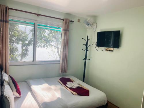 a bedroom with a bed and a window and a tv at Cliff lake hotel cafe and bar in Pokhara