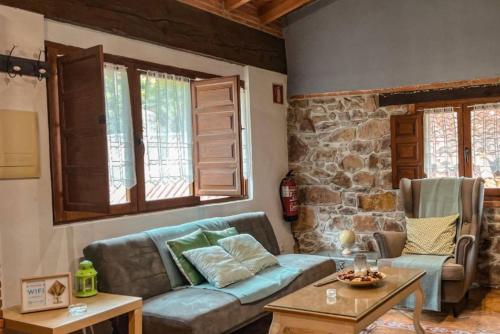 a living room with a couch and a stone wall at Carbayu Senda del Oso in Proaza