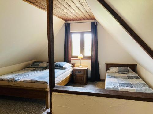 a attic bedroom with two beds and a window at Modryna - Modrzewiowy Dom in Cisna