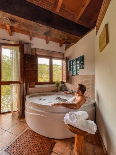 a man sitting in a bath tub in a bathroom at Carbayu Senda del Oso in Proaza