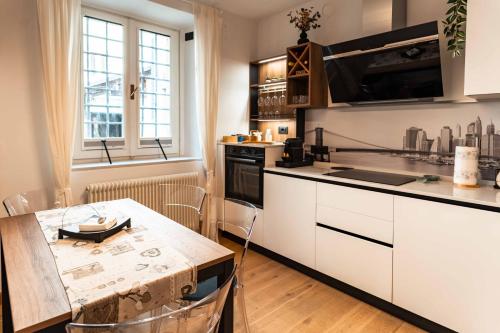 a kitchen with a wooden table and a kitchen with white cabinets at La Chicca in pieno centro storico con SAUNA e Parcheggio gratuito in Udine