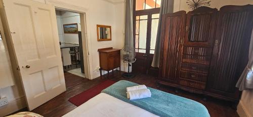 a bedroom with a bed and a dresser and a desk at Kelkiewyn Guesthouse Caledon in Caledon