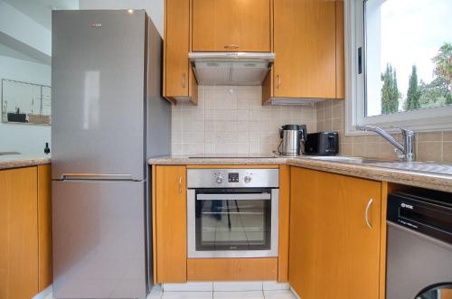a kitchen with wooden cabinets and a stainless steel refrigerator at Pafilia Gardens 6 in Paphos