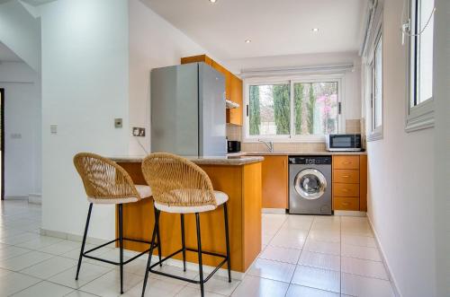 a kitchen with two chairs and a counter with a washing machine at Pafilia Gardens 6 in Paphos