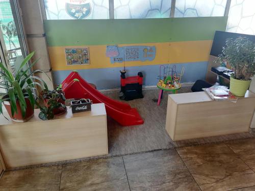 a classroom with two tables and a slide and plants at Hotel Talija in Svilajnac