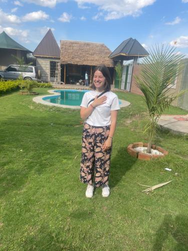 a woman standing in the grass next to a tree at Local Villa Lodge in Arusha