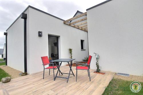 a patio with a table and chairs on a deck at Ty ar bleuenn in Penvénan