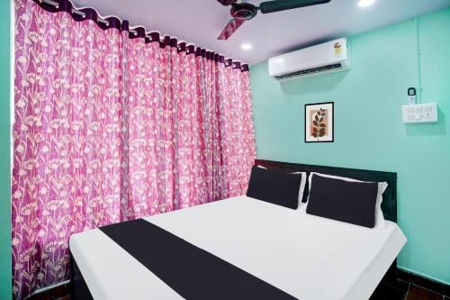 a bedroom with a bed and a pink curtain at Super Hotel O Grill Inn in Dhanbād
