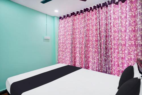 a bedroom with a bed and a pink curtain at Super Hotel O Grill Inn in Dhanbād