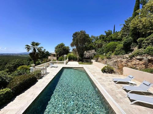 a swimming pool with chairs and a villa at Villa Blanche pour 8 personnes avec piscine privée à La Londes-Les-Maures in La Londe-les-Maures