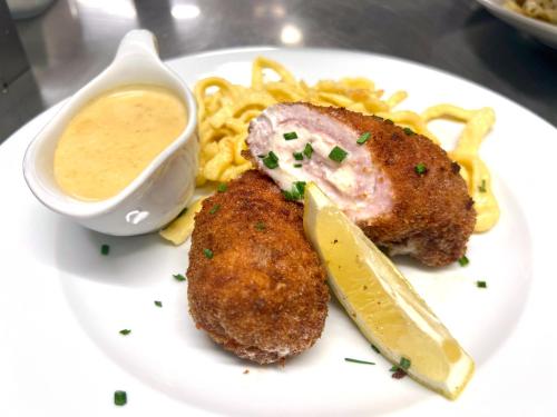 a plate of food with meat and fries and dipping sauce at Hotel Engel Buch in Albbruck