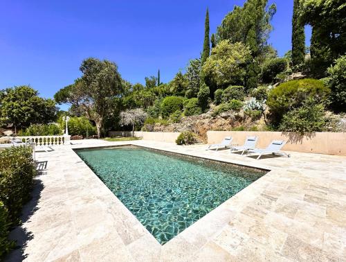 a swimming pool with two white chairs and a swimming pool at Villa Blanche pour 8 personnes avec piscine privée à La Londes-Les-Maures in La Londe-les-Maures