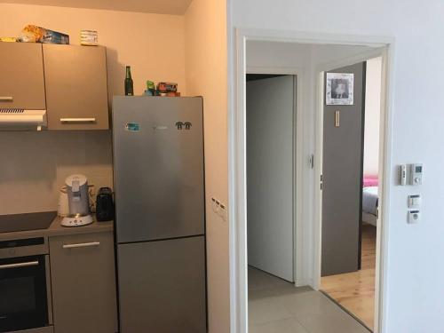 une cuisine avec un réfrigérateur et une porte ouverte dans l'établissement Arcachon centre résidence récente, à Arcachon