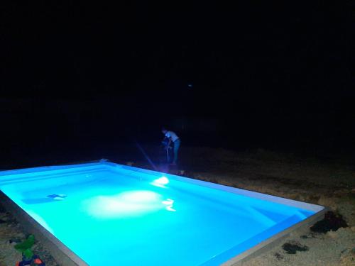 un homme debout dans une piscine la nuit dans l'établissement Château des Cours - Gîte La Providence, à Taillis