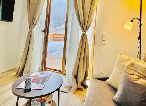 a living room with a table and a couch and a window at Ferienwohnung 'Breitenstein' am Schliersee in Schliersee