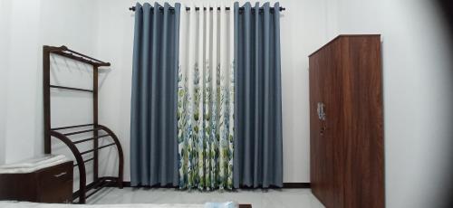 a room with a window with blue curtains at Sandakini Home Rest in Ahangama