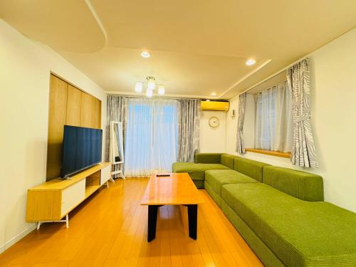 a living room with a green couch and a television at PUSU-OKUBO House 3LDK-SJ0079 in Tokyo
