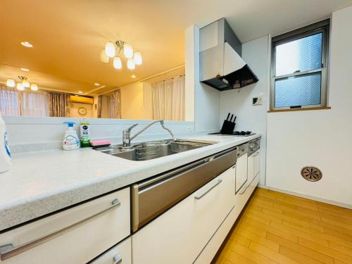 a kitchen with white counters and a sink and a window at PUSU-OKUBO House 3LDK-SJ0079 in Tokyo
