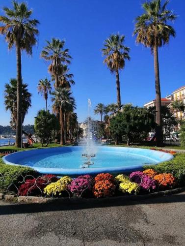a fountain in a park with palm trees and flowers at Casa Noemi, nel cuore di Varazze, ad un passo dal mare in Varazze