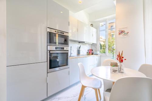 une cuisine blanche avec une table et des chaises blanches dans l'établissement Charmant 2P au cœur de Nice, à Nice