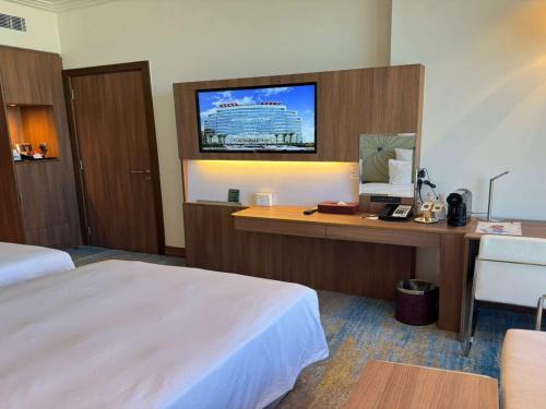 a hotel room with a bed and a desk with a computer at Novotel Jazan in Jazan