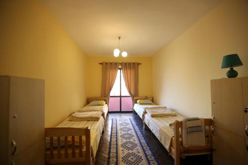 three beds in a room with a window at Cosy Hostel Tirana in Tirana