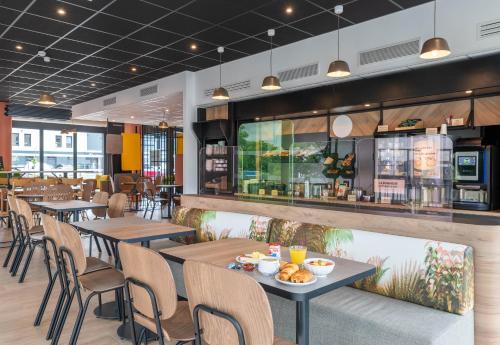 un restaurant avec des tables, des chaises et un comptoir dans l'établissement B&B HOTEL Villefranche-sur-Saône Sud, à Villefranche-sur-Saône