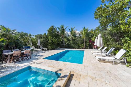 a swimming pool with chairs and a table and an umbrella at Wyakha 2 Ocean View in Long Bay Hills