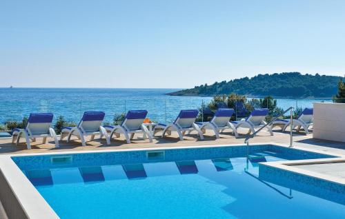 a pool with chairs and the ocean in the background at Nice Apartment In Rogoznica With Sauna in Rogoznica