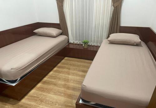 a bedroom with two beds and a window at Homestay Omah Embun in Godean