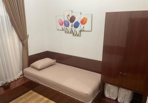 a small bed in a room with a painting on the wall at Homestay Omah Embun in Godean