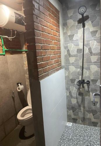 a bathroom with a toilet and a brick wall at Homestay Omah Embun in Godean